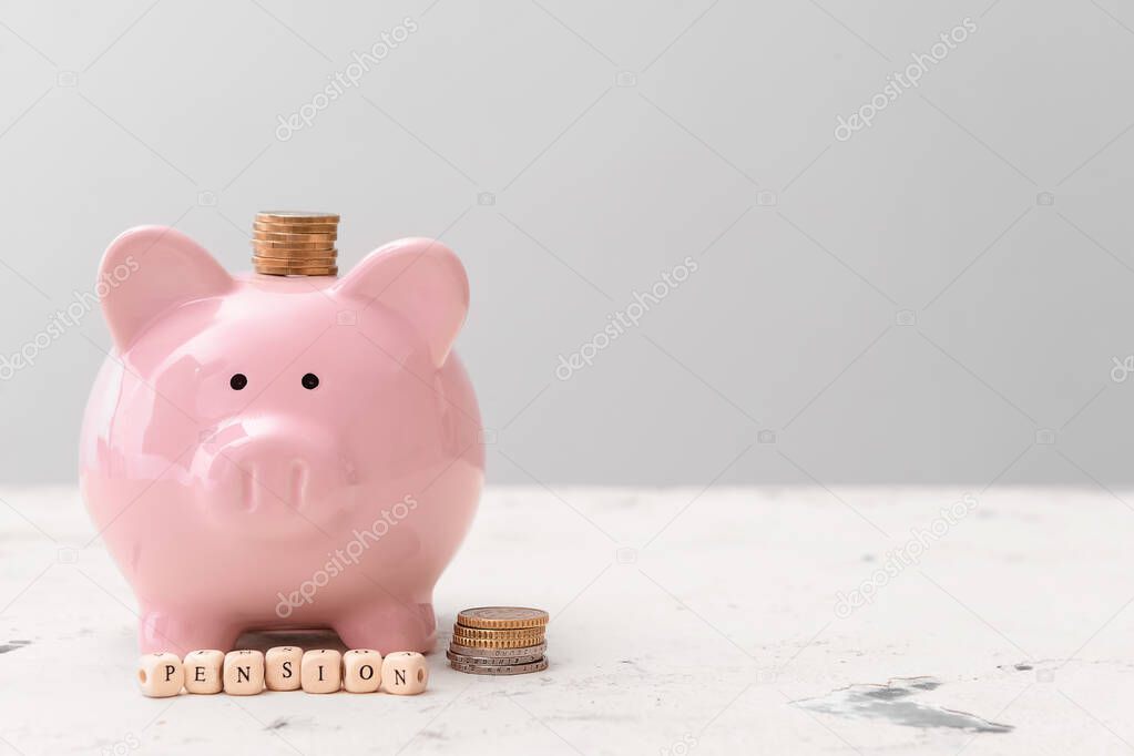 Piggy bank with coins and word PENSION on table