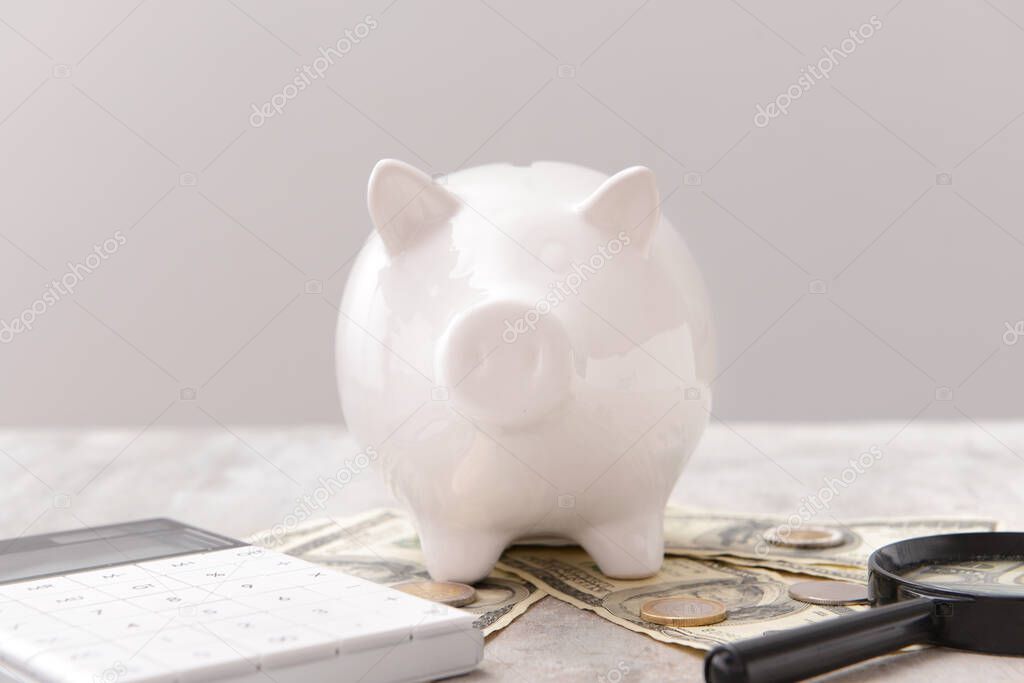 Piggy bank with money, calculator and magnifier on grey background. Concept of pension
