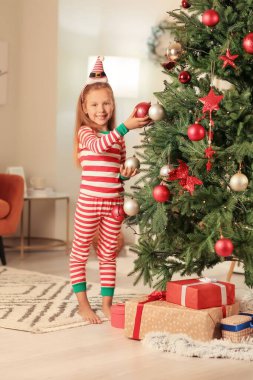 Evde Noel ağacı süsleyen tatlı küçük kız.