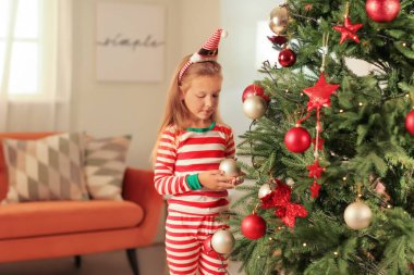 Evde Noel ağacı süsleyen tatlı küçük kız.