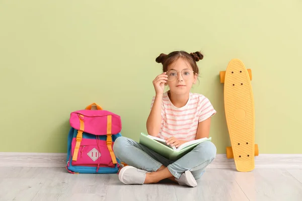 Klein Schoolmeisje Met Skateboard Notebook Zitten Buurt Van Kleur Muur — Stockfoto