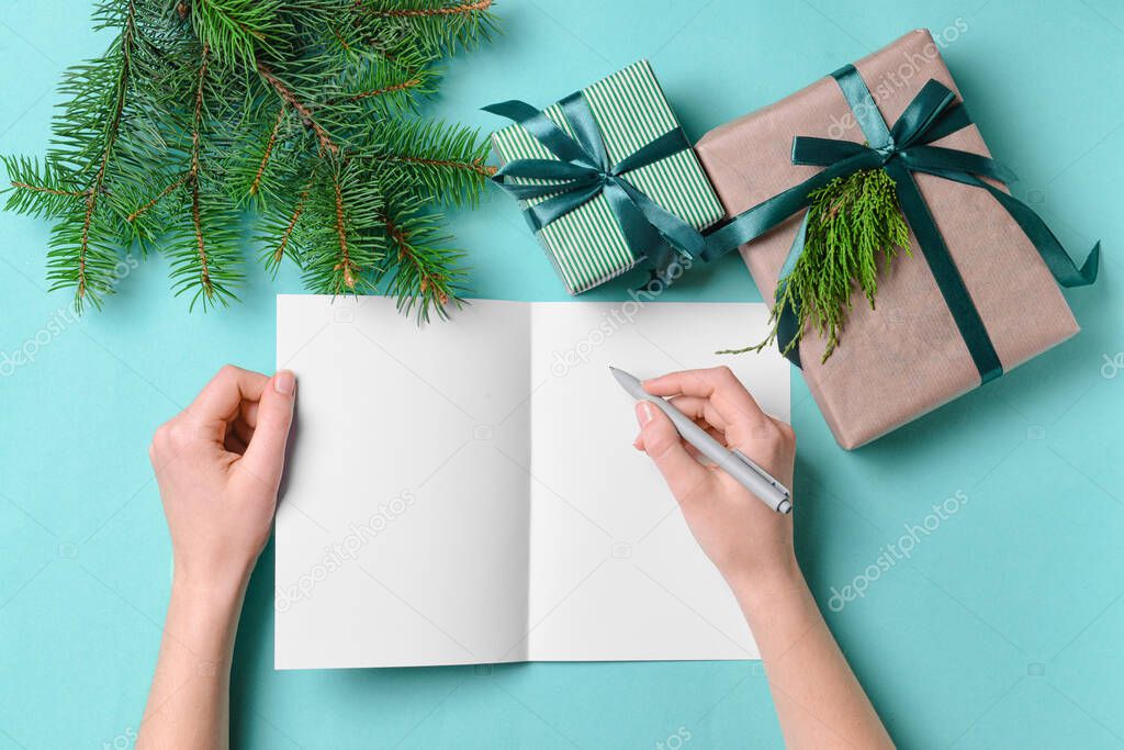 Female hands with blank card and Christmas gifts on color background