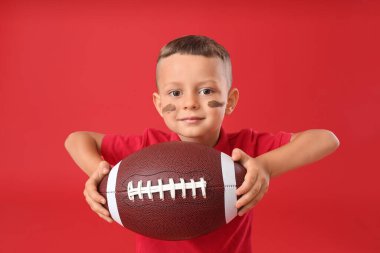 Arka planda rugby topu olan küçük çocuk