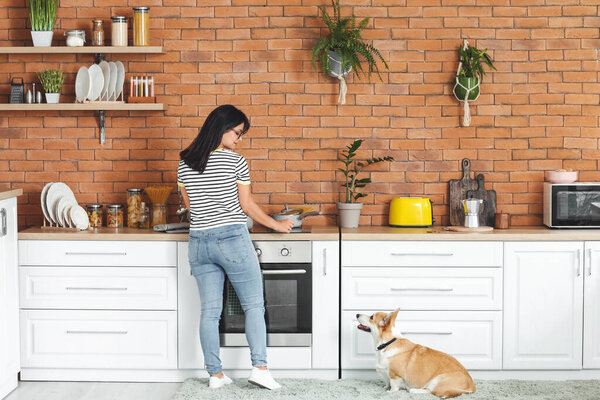 Женщина с милой корги собака на кухне дома