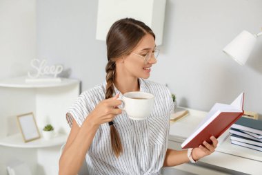 Evde kitap okuyan güzel genç bir kadın.