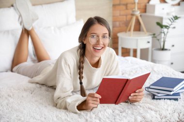 Evde kitap okuyan güzel genç bir kadın.