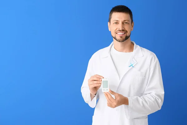 Doctor with digital glucometer on color background. Diabetes concept