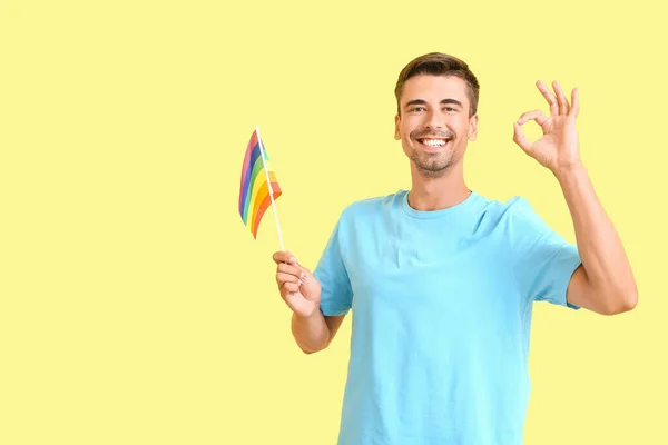色の背景でOkを示すLgbtの旗を持つ若い男 — ストック写真