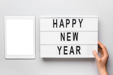 Tablet bilgisayarı ve tabletli kadın eli açık arkaplanda Mutlu Yıllar metniyle