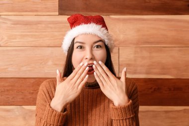 Ahşap arka planda Noel Baba şapkalı genç kadın.