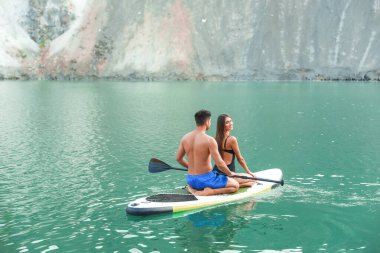 Genç çift nehirde sörf yapmak için sörf tahtası kullanıyor.