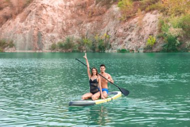 Genç çift nehirde sörf yapmak için sörf tahtası kullanıyor.