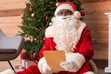 Afro-Amerikan Noel Baba evde mektup okuyor.