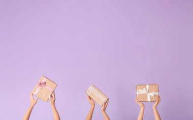 Renk arkaplanında hediye kutuları olan eller
