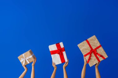 Renk arkaplanında hediye kutuları olan eller
