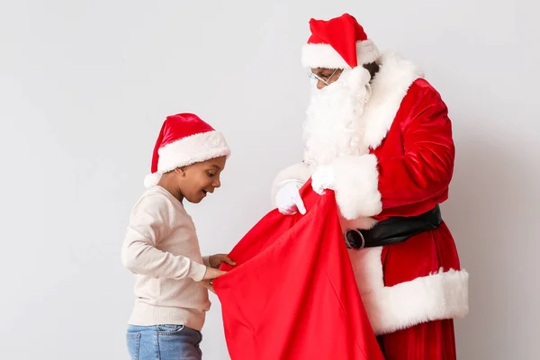 Menino Afro Americano Escolhendo Presente Saco Papai Noel Fundo Claro — Fotografia de Stock