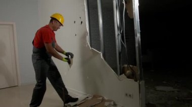 Erkek müteahhit, alçı taşı duvarını içeride kırıyor.