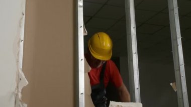 Erkek müteahhit, alçı taşı duvarını içeride kırıyor.