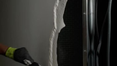 Erkek müteahhit alçıtaşı duvarını içeride kırıyor, yakın plan.
