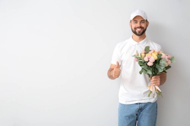 Elinde bir buket çiçekle teslimatçı arka planda baş parmağını kaldırıyor.