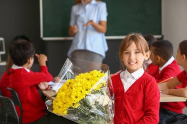 Sınıfta öğretmenine buket getiren küçük okul kızı.
