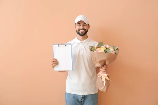 Delivery man with bouquet of flowers on color background