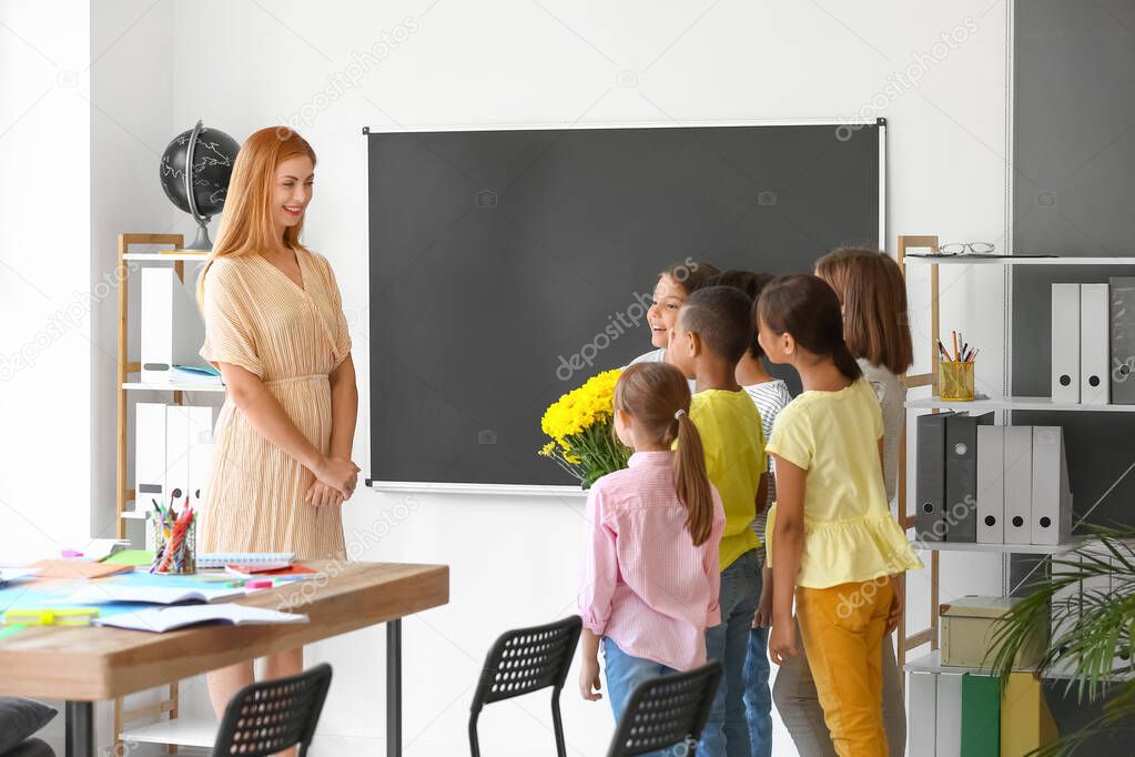 Schoolchildren greeting their teacher in classroom