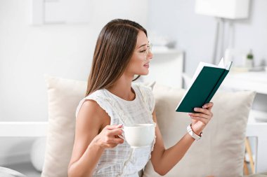 Evde kitap okuyan güzel genç bir kadın.