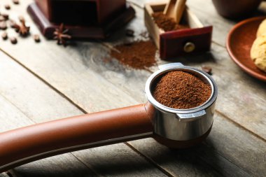 Ahşap zemin üzerinde kahve tozu olan bir Portafilter.