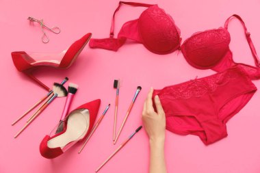 Renkli iç çamaşırları, ayakkabıları ve aksesuarları olan bir kadın eli.