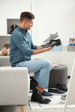 Modern mağazada yeni ayakkabılar seçen bir adam