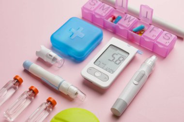 Renk arkaplanında ilaç ve tükenmez kalem bulunan glukometre. Diyabet kavramı