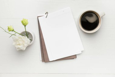 Çiçekli boş defter ve beyaz arka planda bir fincan kahve.