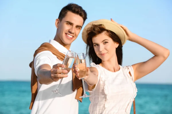 一对快乐的年轻夫妇在海滩上喝香槟 — 图库照片
