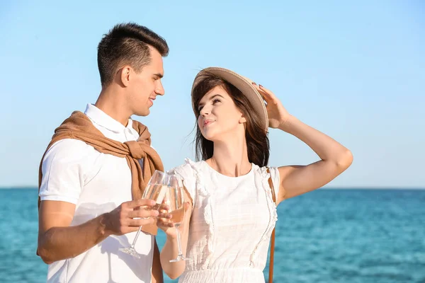 一对快乐的年轻夫妇在海滩上喝香槟 — 图库照片
