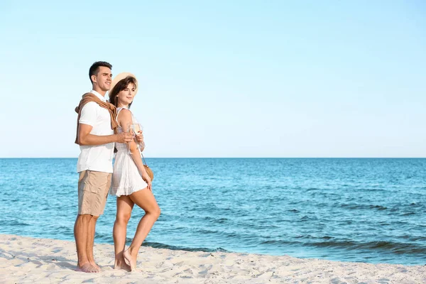 幸せな若いカップル飲むシャンパンで海のビーチ — ストック写真