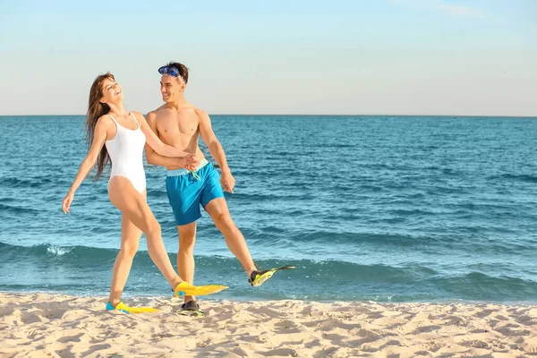 幸せな若いカップルでパドルで海のビーチを歩く — ストック写真