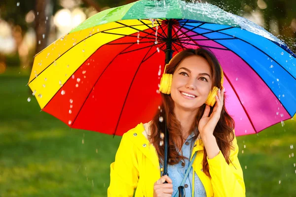 美しいです若いです女性で傘を着てレインコートで公園 — ストック写真