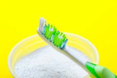 Renkli arkaplanda diş fırçası ve toz, yakın plan