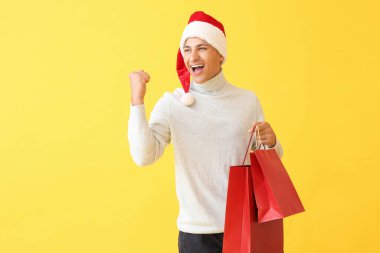 Noel Baba şapkalı ve renkli çantalı mutlu bir adam.