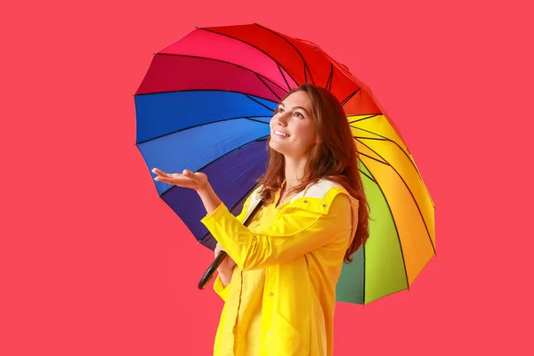Yağmurluk Giymiş Arka Planda Şemsiyesi Olan Güzel Genç Bir Kadın — Stok fotoğraf