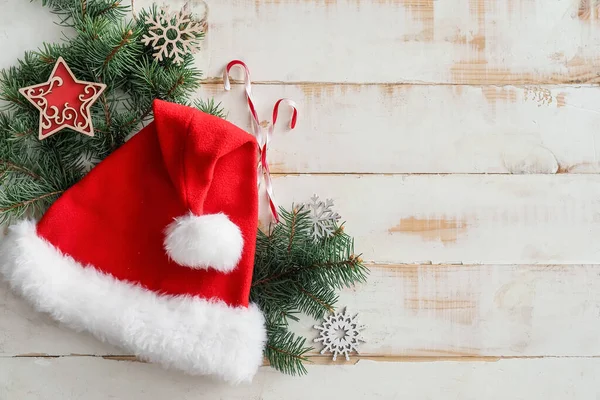 白い木製の背景にサンタクロースの帽子とクリスマスの組成 — ストック写真