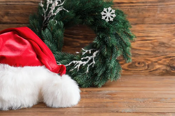 サンタクロースの帽子とともにクリスマスリース上の色背景 — ストック写真