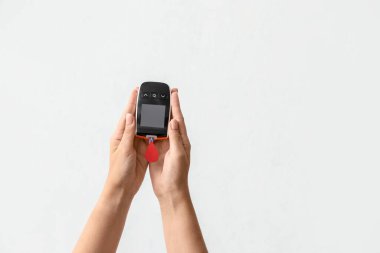 Glukometresi olan kadın eller ve arka planda kan damlaları. Diyabet kavramı