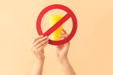 Plastik bardaklı kadın eller ve arka planda dur işareti. Ekoloji kavramı