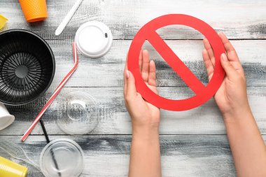 Plastik çöpü olan kadın eller ve tahta arka planda dur işareti. Ekoloji kavramı