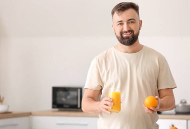 Mutfakta portakallı ve meyve suyu olan adam.