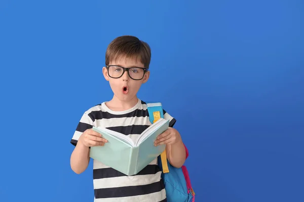 Überraschter Kleiner Schüler Mit Buch Auf Farbigem Hintergrund — Stockfoto