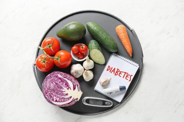 Sebzeler, diABETES yazılı defter, beyaz arkaplanda lamba kalem ve glukometre