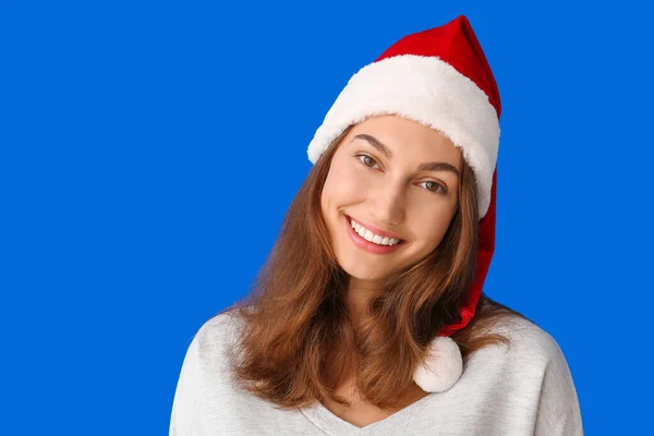 戴着彩色背景圣诞老人帽的年轻漂亮的女人 — 图库照片